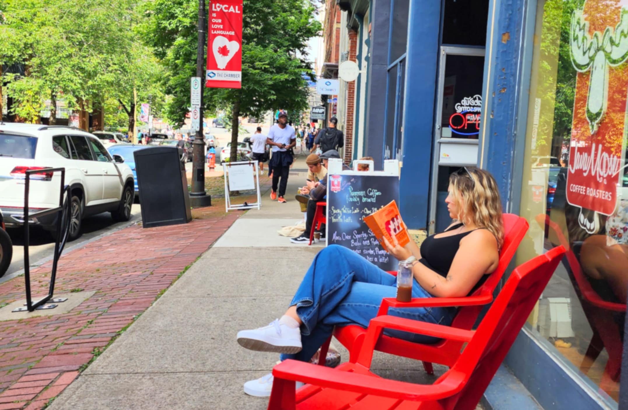 Uptown Saint John in the summer a women reading a book on the sidewalk infront of a cafe