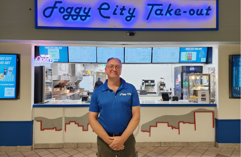 Owner Jason Gomke smiling inside Foggy City Takeout in Uptown Saint John — proudly operating both Foggy City Takeout and Foggy City Sweets & Souvenirs
