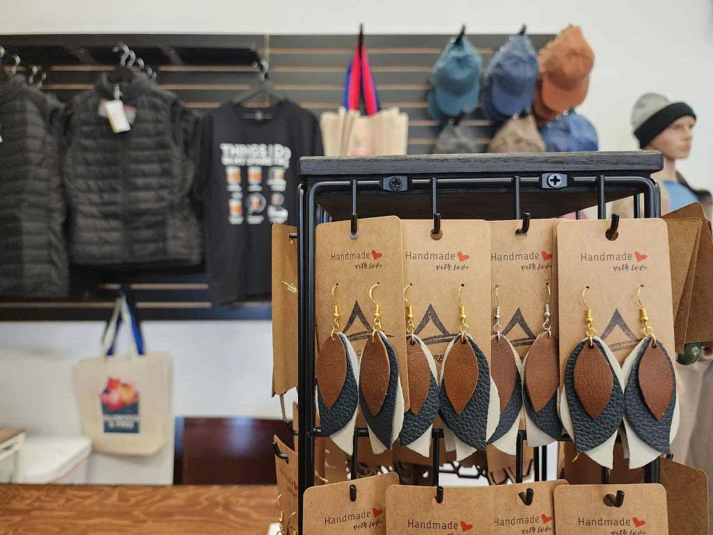 Handmade leather earrings in neutral tones displayed on branded cards at Ankar Creative.