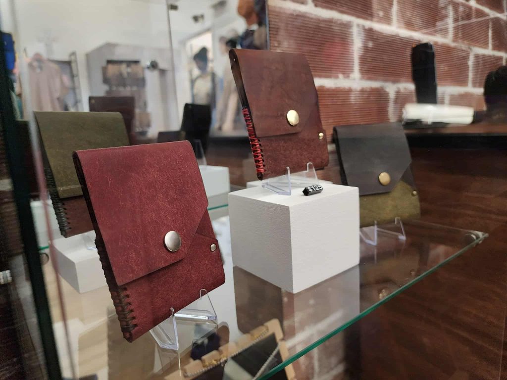 Handcrafted leather wallets displayed on stands inside a glass case at Ankar Creative.