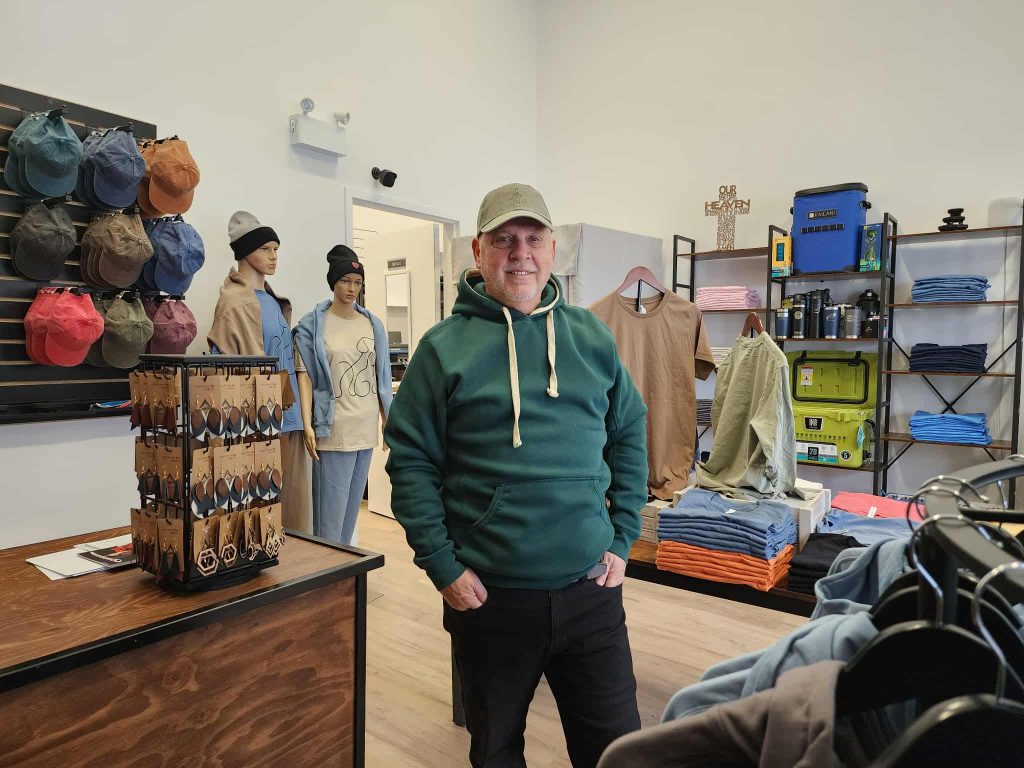 Fernand Pelletier standing inside Ankar Creative’s showroom, surrounded by custom apparel and handcrafted goods.