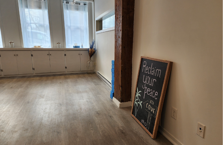 A chalkboard sign reading “Reclaim your peace” rests inside Cove Yoga, reflecting the studio’s calm, intentional approach to learning and practice.