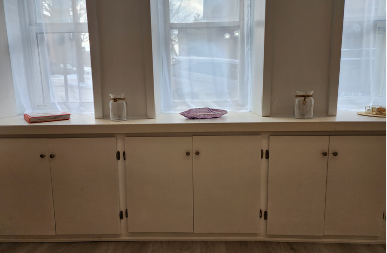 Soft daylight streams through tall windows above built-in cabinets inside Cove Yoga, creating a calm and minimalist studio atmosphere.