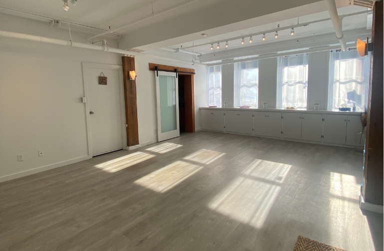 Wide view of the Cove Yoga studio in Uptown Saint John, with open floor space, natural light, and a peaceful, training-focused layout.