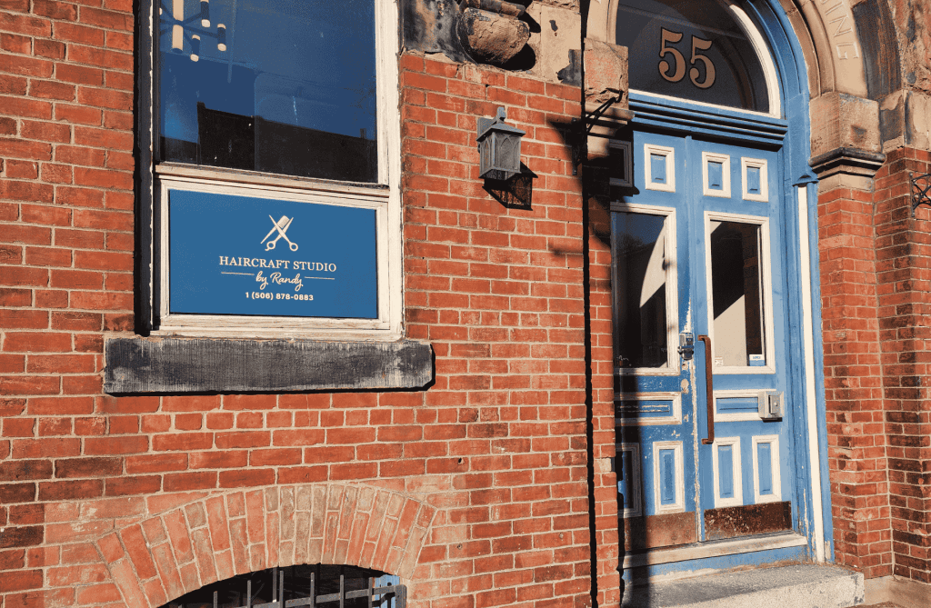 Exterior of Haircraft Studio by Randy on Canterbury Street, featuring a historic brick building and blue doorway in Uptown Saint John.