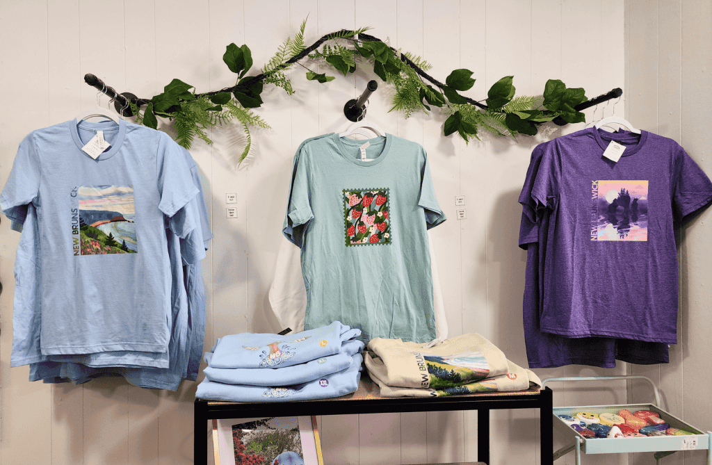 T-shirts with New Brunswick and Maritime-inspired artwork displayed inside Memory Made Gifts in Uptown Saint John.