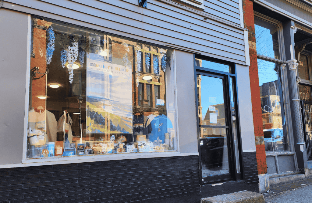 Exterior of Memory Made Gifts on Germain Street in Uptown Saint John with large display windows and historic brick buildings reflected in the glass.