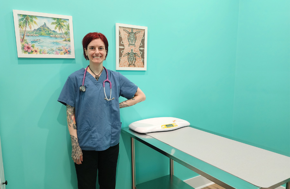 Dr. Alison Messina standing in a turquoise exam room at Uptown Animal Clinic in Uptown Saint John with a pet exam table and wall art.