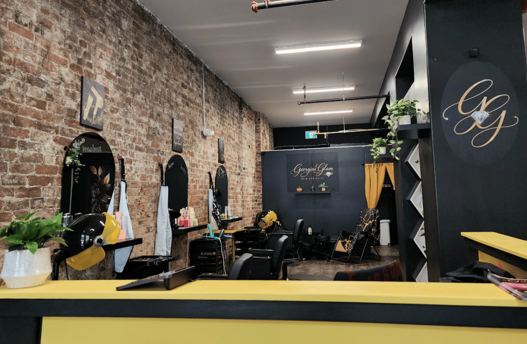 Reception area and salon interior at Georgia's Glam featuring exposed brick and modern salon furnishings.