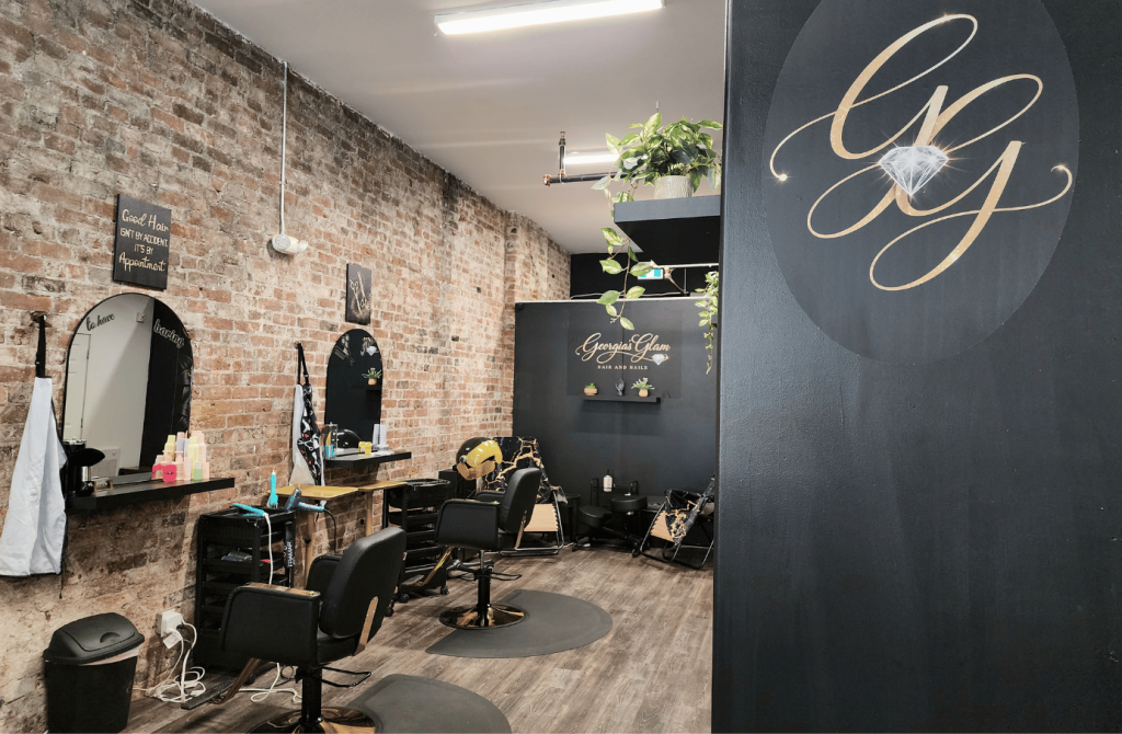 Interior of Georgia's Glam featuring exposed brick walls, styling stations, and a welcoming salon space in Uptown Saint John.